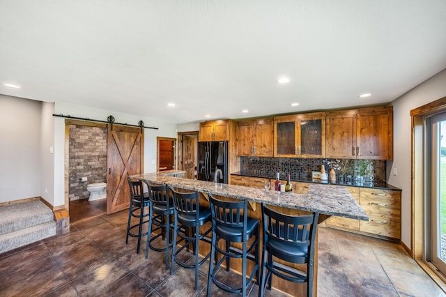 29437 141st Ave, Lanesburgh Twp, MN 56071 - kitchen with black refrigerator with ice dispenser, a barn door, brown cabinets, tasteful backsplash, and a breakfast bar