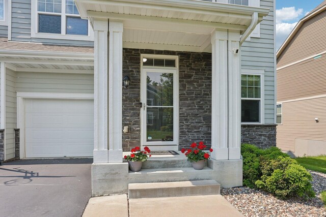 18482 Aubrie Ct, Eden Prairie, MN 55347 - entrance to property featuring stone siding, an attached garage, covered porch, and driveway