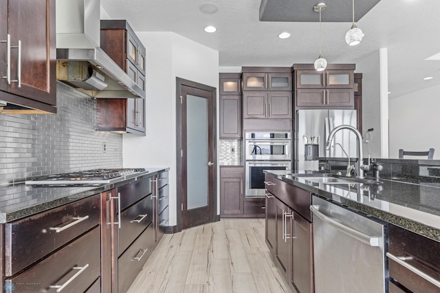 3004 6th St E, West Fargo, ND 58078 - kitchen with stainless steel appliances, wall chimney range hood, a sink, light wood-type flooring, and dark stone countertops