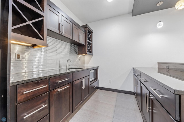 3004 6th St E, West Fargo, ND 58078 - kitchen featuring a sink, stainless steel microwave, baseboards, decorative backsplash, and dark brown cabinets
