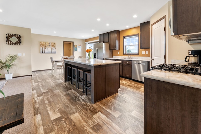 16536 Hook Cir, Pokegama Twp, MN 55030 - kitchen featuring appliances with stainless steel finishes, light wood-type flooring, a breakfast bar, a kitchen island, and light stone countertops