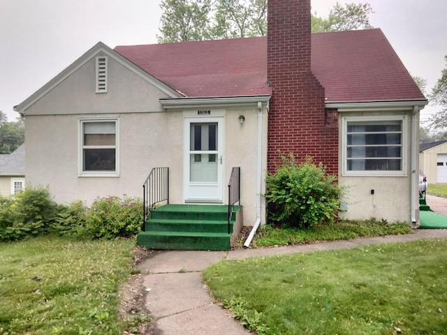 1193 County Road B E, Maplewood, MN 55109 - view of front of home with a chimney, a front lawn, stucco siding, and a shingled roof