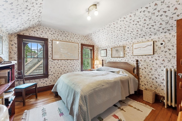 1913 River Pkwy, Minneapolis, MN 55414 - bedroom featuring radiator heating unit, wallpapered walls, wood finished floors, and vaulted ceiling