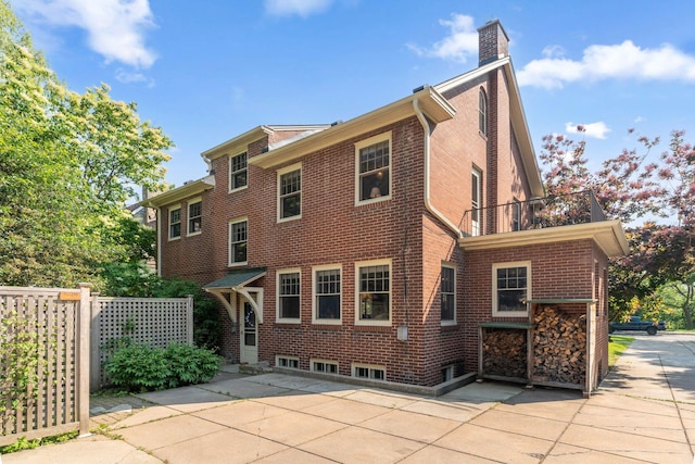1913 River Pkwy, Minneapolis, MN 55414 - back of house with a balcony, brick siding, a patio, and a chimney