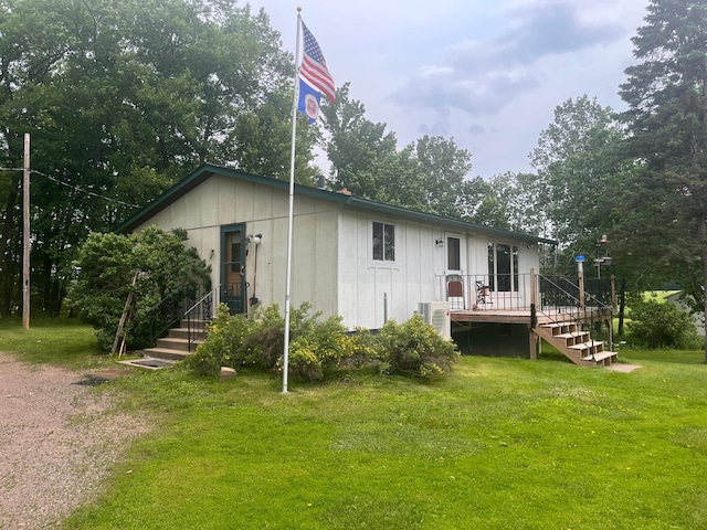 4503 Hawk Ridge Rd, Grasston, MN 55030 - back of property with stairway, a lawn, a deck, board and batten siding, and view of wooded area