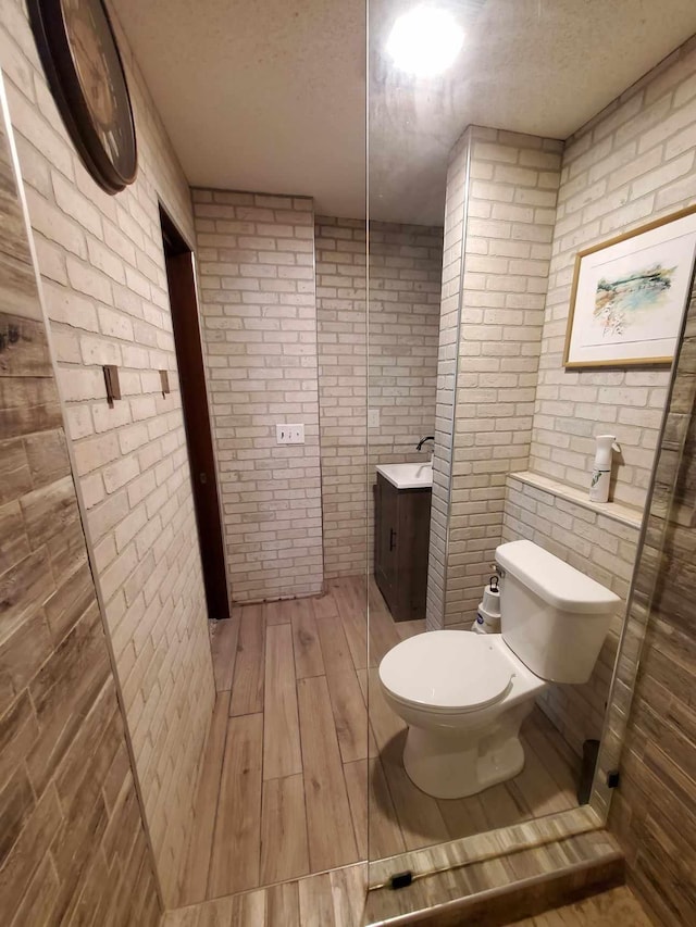 12383 Midway Cir NE, Blaine, MN 55449 - bathroom featuring brick wall, vanity, wood finished floors, and a textured ceiling