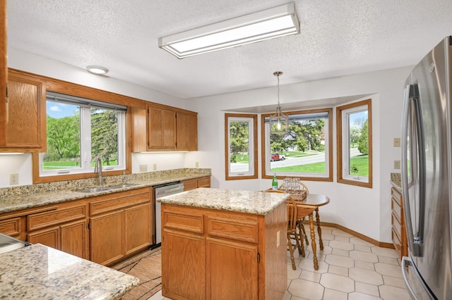 3924 Denmark Ave, Eagan, MN 55123 - kitchen featuring appliances with stainless steel finishes, a sink, a textured ceiling, a kitchen island, and hanging light fixtures