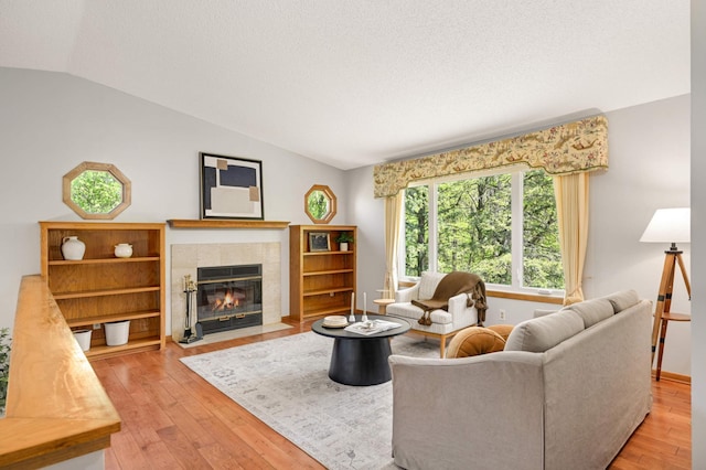 3924 Denmark Ave, Eagan, MN 55123 - living room featuring lofted ceiling, a tiled fireplace, hardwood / wood-style flooring, a textured ceiling, and baseboards