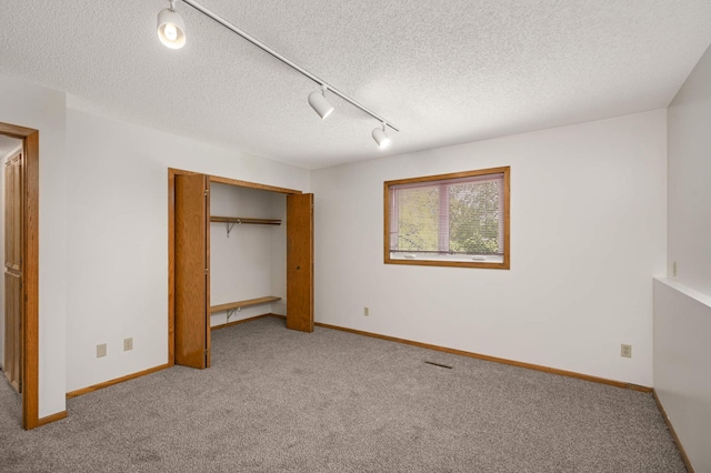 3924 Denmark Ave, Eagan, MN 55123 - unfurnished bedroom with rail lighting, carpet, a closet, baseboards, and a textured ceiling