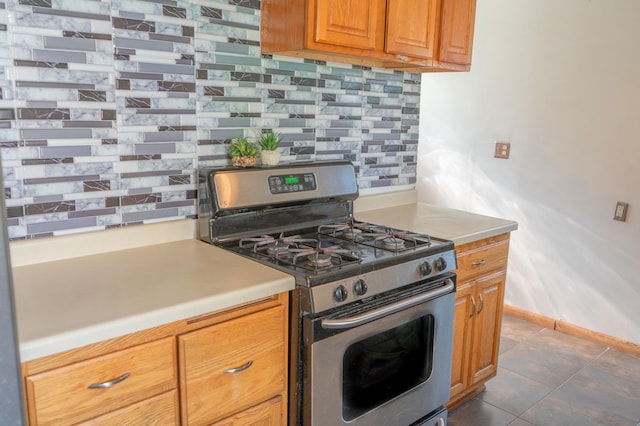 2161 Ross Ave E, Saint Paul, MN 55119 - kitchen featuring gas range, decorative backsplash, brown cabinets, light countertops, and dark tile patterned floors