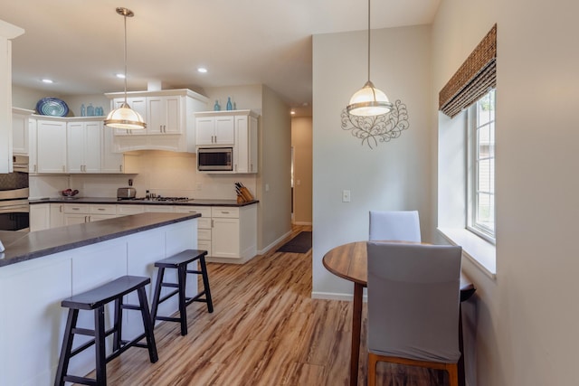 1614 8th St, Grand Rapids, MN 55744 - kitchen with stainless steel appliances, dark countertops, a kitchen bar, light wood-style flooring, and recessed lighting