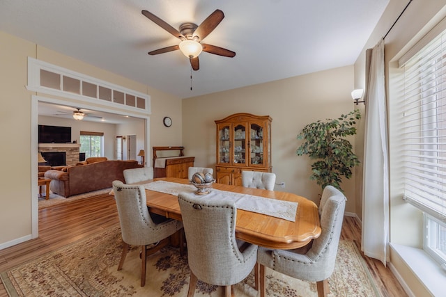 1614 8th St, Grand Rapids, MN 55744 - dining area featuring ceiling fan, light wood-style floors, a fireplace, and baseboards