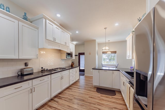 1614 8th St, Grand Rapids, MN 55744 - kitchen featuring appliances with stainless steel finishes, dark countertops, a peninsula, tasteful backsplash, and white cabinets