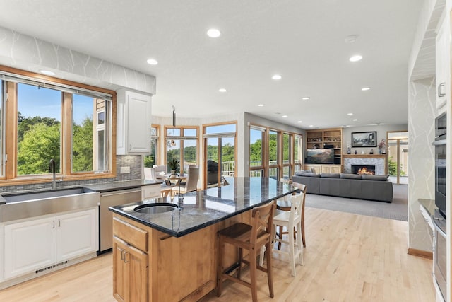 18715 24th Ave N, Plymouth, MN 55447 - kitchen with a sink, stainless steel appliances, recessed lighting, a warm lit fireplace, and light wood-style floors