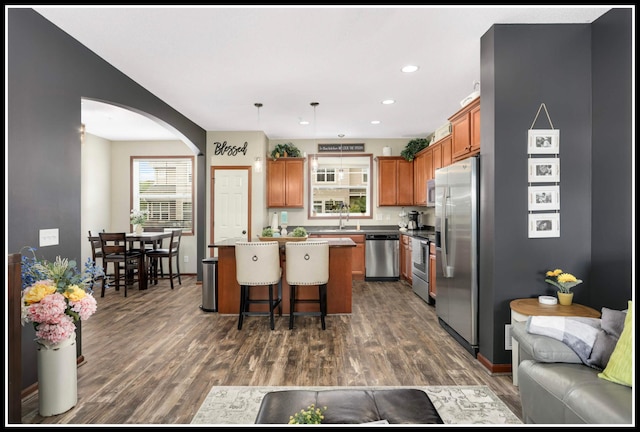 8065 Kirkwood Ln N Unit 82, Maple Grove, MN 55369 - kitchen featuring appliances with stainless steel finishes, arched walkways, brown cabinets, a center island, and dark wood finished floors