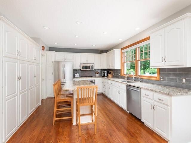1776 Lockridge Ct, Waconia, MN 55387 - kitchen featuring stainless steel appliances, a sink, light stone counters, white cabinets, and wood finished floors