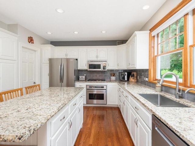 1776 Lockridge Ct, Waconia, MN 55387 - kitchen featuring appliances with stainless steel finishes, dark wood-style flooring, backsplash, white cabinetry, and light stone counters