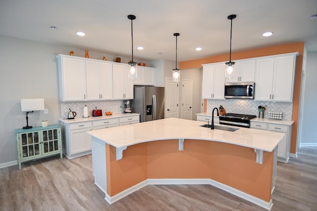 4837 Avery Ct, Eagan, MN 55123 - kitchen featuring stainless steel appliances, light wood-style floors, a center island with sink, backsplash, and white cabinetry