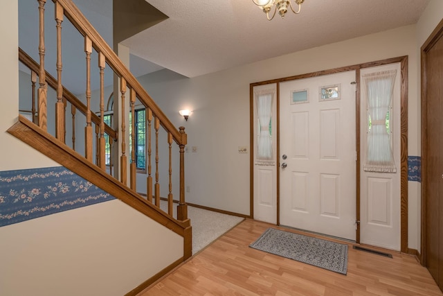 957 Belvista Dr, North Mankato, MN 56003 - entryway featuring wood finished floors, stairs, baseboards, and a textured ceiling