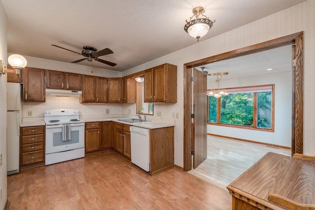 957 Belvista Dr, North Mankato, MN 56003 - kitchen featuring white appliances, under cabinet range hood, a sink, brown cabinets, and light wood finished floors