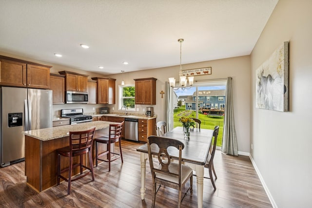 12083 79th St NE, Otsego, MN 55330 - kitchen featuring stainless steel appliances, brown cabinets, a center island, a sink, and a chandelier