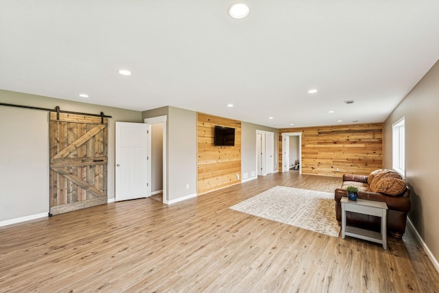 12083 79th St NE, Otsego, MN 55330 - unfurnished living room with a barn door, recessed lighting, baseboards, light wood-style flooring, and wooden walls