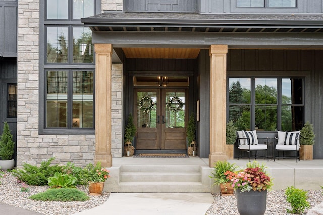 11278 Eastwood Ave SE, Delano, MN 55328 - doorway to property featuring french doors, stone siding, covered porch, and board and batten siding