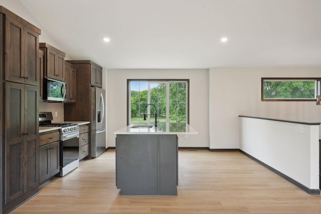 2660 128th Ave NW, Coon Rapids, MN 55434 - kitchen with appliances with stainless steel finishes, a sink, light countertops, light wood-style floors, and an island with sink