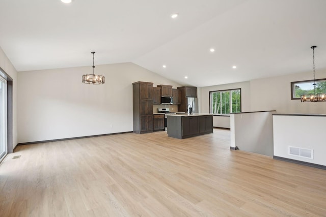 2660 128th Ave NW, Coon Rapids, MN 55434 - kitchen featuring a chandelier, stainless steel appliances, light countertops, vaulted ceiling, and a center island with sink