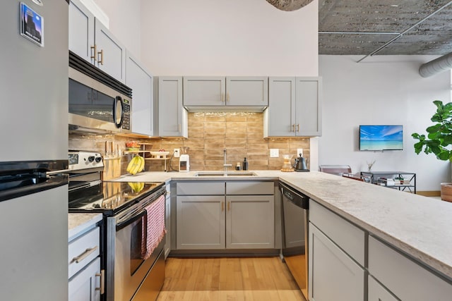 521 7th St Unit 416, Minneapolis, MN 55415 - kitchen featuring stainless steel appliances, light wood-style flooring, gray cabinets, and decorative backsplash