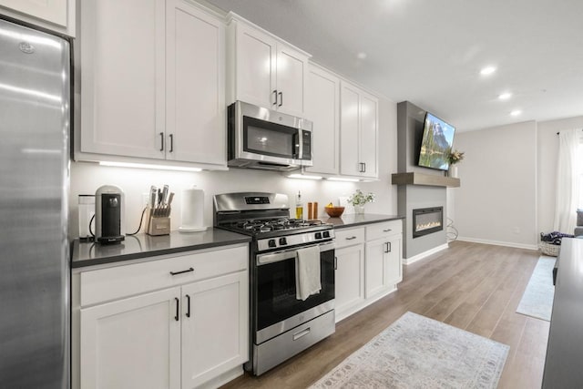 1517 Timberwood Ln, West Saint Paul, MN 55118 - kitchen featuring appliances with stainless steel finishes, dark countertops, light wood finished floors, recessed lighting, and white cabinetry