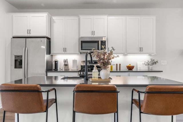 1517 Timberwood Ln, West Saint Paul, MN 55118 - kitchen featuring appliances with stainless steel finishes, white cabinets, a kitchen breakfast bar, and a kitchen island with sink