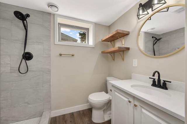 7609 65th Ave N, Brooklyn Park, MN 55428 - bathroom featuring tiled shower, vanity, toilet, wood finished floors, and baseboards