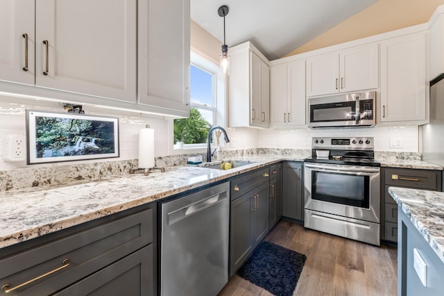 1641 Possum Way, New Richmond, WI 54017 - kitchen featuring appliances with stainless steel finishes, vaulted ceiling, dark wood-style flooring, backsplash, and white cabinetry