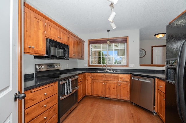 29259 Wildwood Rd, Chisago City, MN 55013 - kitchen featuring black appliances, brown cabinetry, light wood finished floors, dark countertops, and a textured ceiling