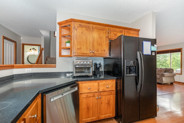 29259 Wildwood Rd, Chisago City, MN 55013 - kitchen with dishwasher, black fridge with ice dispenser, brown cabinets, dark countertops, and a textured ceiling
