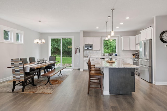 7465 Glengarry Pl, Eden Prairie, MN 55344 - kitchen with appliances with stainless steel finishes, a center island, white cabinetry, decorative backsplash, and dark wood-style flooring
