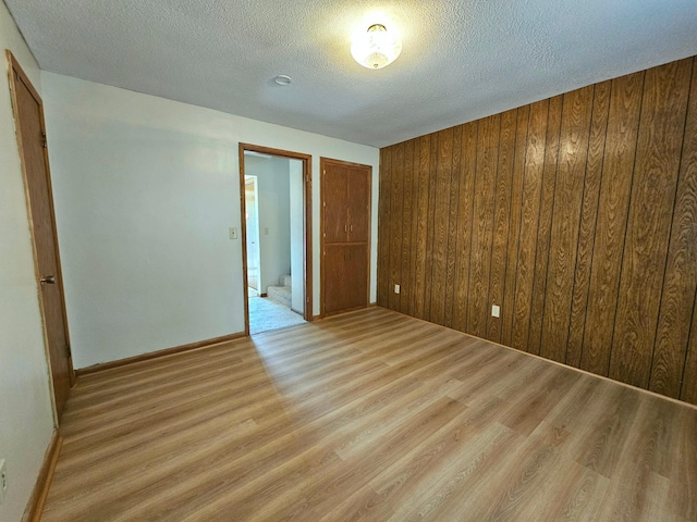 735 Main St N, Hutchinson, MN 55350 - empty room with light wood-style flooring, a textured ceiling, and wooden walls