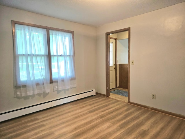 735 Main St N, Hutchinson, MN 55350 - unfurnished room featuring a baseboard heating unit and wood finished floors