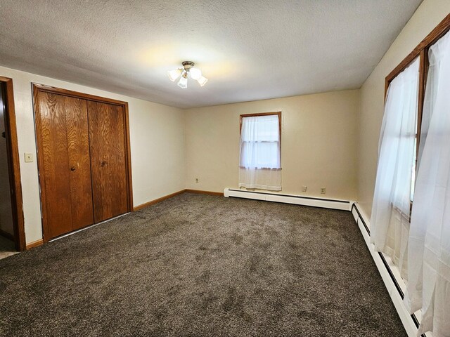 735 Main St N, Hutchinson, MN 55350 - unfurnished bedroom with a baseboard radiator, dark colored carpet, and a textured ceiling