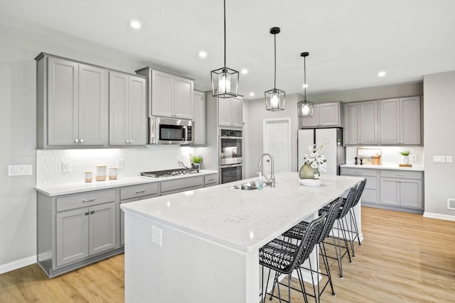 14645 Cloquet St, Dayton, MN 55327 - kitchen featuring gray cabinets, appliances with stainless steel finishes, recessed lighting, light wood finished floors, and tasteful backsplash