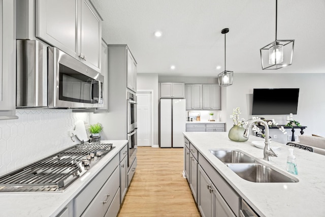 14645 Cloquet St, Dayton, MN 55327 - kitchen with gray cabinetry, stainless steel appliances, light wood-style floors, tasteful backsplash, and decorative light fixtures