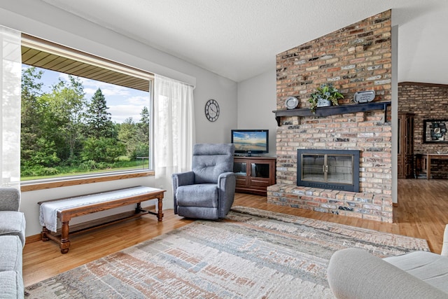 17000 Jackal St NW, Ramsey, MN 55303 - living area featuring lofted ceiling, wood finished floors, a fireplace, and a textured ceiling