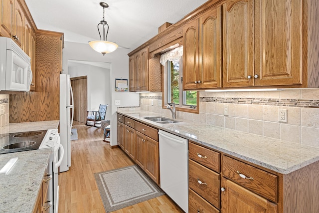 17000 Jackal St NW, Ramsey, MN 55303 - kitchen featuring white appliances, backsplash, light wood-type flooring, brown cabinetry, and light stone countertops