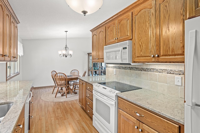 17000 Jackal St NW, Ramsey, MN 55303 - kitchen featuring white appliances, light wood-style flooring, tasteful backsplash, brown cabinets, and light stone counters