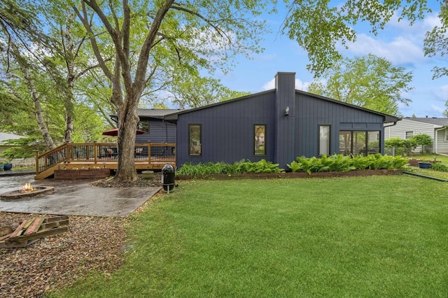 2500 Ensign Ave N, Golden Valley, MN 55427 - rear view of house featuring a fire pit, a wooden deck, a lawn, and a patio area