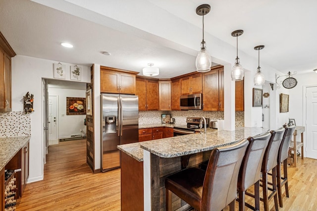 2500 Ensign Ave N, Golden Valley, MN 55427 - kitchen featuring stainless steel appliances, a peninsula, light wood-type flooring, decorative backsplash, and a breakfast bar area