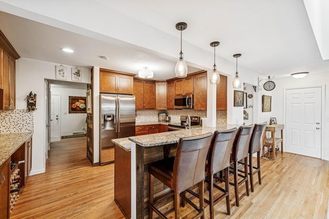 2500 Ensign Ave N, Golden Valley, MN 55427 - kitchen featuring stainless steel appliances, a peninsula, light wood-style flooring, tasteful backsplash, and a breakfast bar