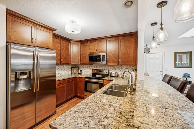 2500 Ensign Ave N, Golden Valley, MN 55427 - kitchen featuring appliances with stainless steel finishes, light stone counters, a peninsula, light wood finished floors, and brown cabinets