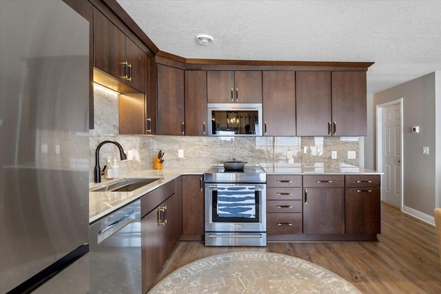 1702 Lakeshore Dr Unit 3, Lake City, MN 55041 - kitchen featuring appliances with stainless steel finishes, light wood-style flooring, tasteful backsplash, a textured ceiling, and dark brown cabinets